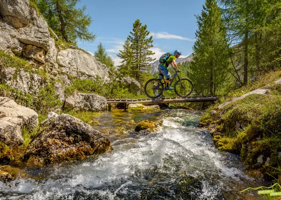 Ciclista di mountain bike attraversa un paesaggio roccioso spettacolare nel Parco Naturale Fanes-Sennes-Braies vicino al Kronplatz in Valle Pusteria